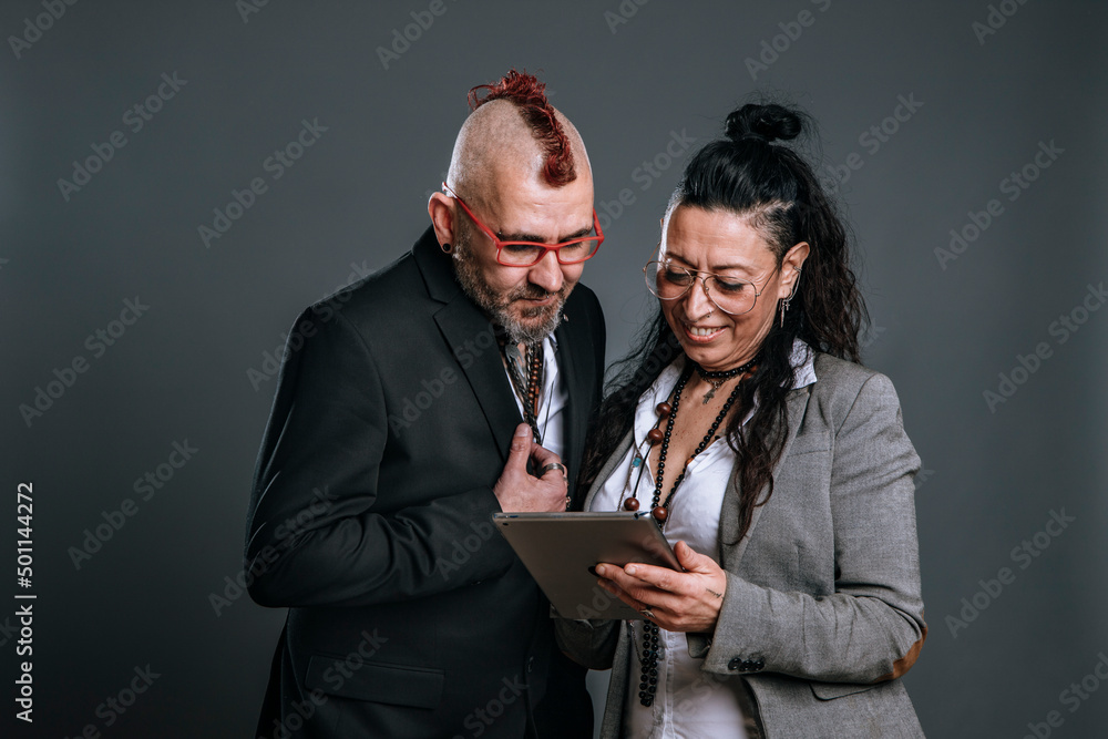 punk-style man and woman wear jacket suits and look at tablet in studio shot punk-style man and woman wear jacket suits and look at tablet in studio shot