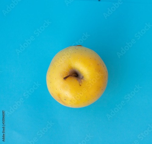 yellow apple on blue background, healthy food concept