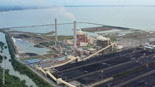High angle pull out shot capturing large coalfield and industrial ultra-supercritical coal-fired power plant with smokes raising from chimney located at costal area of Manjung, Perak, Malaysia. photo