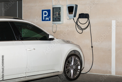 Electric Car Charging  with the Power Cable Supply Plugged in Garage Car Parking. Charging Car. Eco-friendly alternative energy concept.