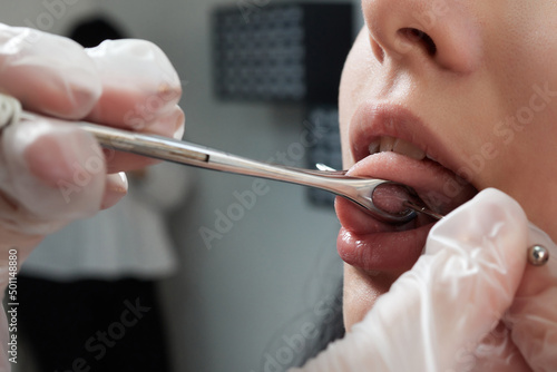 Tongue piercing operation Professional holding the jewel. photo