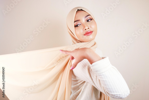 Muslim woman wearing traditional wear and hijab isolated on white background. Hijab is creatively made flying. Idul Fitri and hijab fashion concept. photo