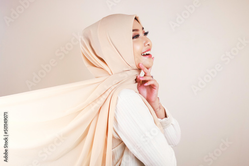 Muslim woman wearing traditional wear and hijab isolated on white background. Hijab is creatively made flying. Idul Fitri and hijab fashion concept. photo