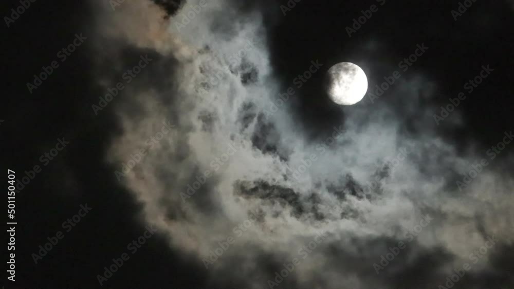 Clouds passing in front of an almost full April moon at night Clouds passing in front of an almost full April moon at night