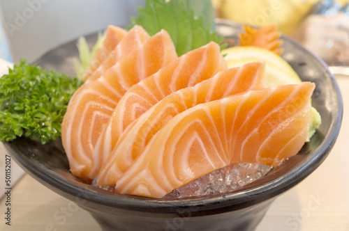 Delicious fresh salmon sashimi is famous appetizer or dinner preparation in restaurant. Sashimi is a Japanese delicacy consisting of fresh raw fish into thin pieces and often eaten with soy sauce.