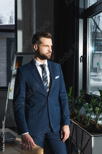 Bild auf Leinwand serious businessman in suit looking away while standing in office