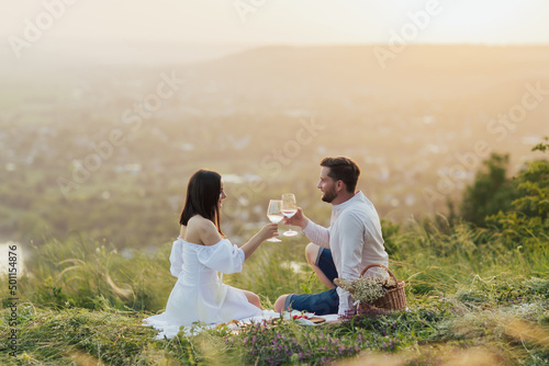 Obraz na płótnie Happy couple drinking wine on the hill at beautiful summer day. Having fun at party in summer. w salonie