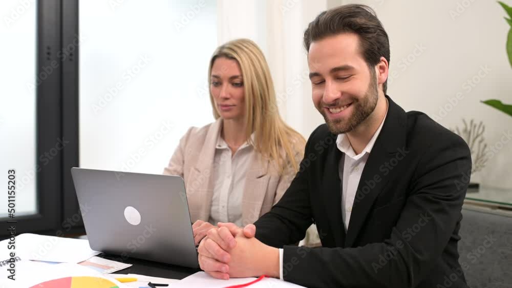 Young attractive man and woman working with papers and laptop in modern office. Blonde girl making notes on paper documents while working with a laptop Young attractive man and woman working with papers and laptop in modern office. Blonde girl making notes on paper documents while working with a laptop