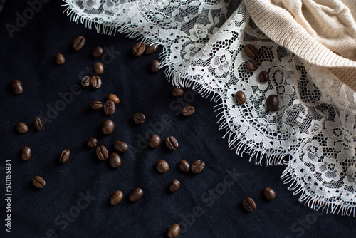Fototapeta Naklejka Na Ścianę i Meble -  Coffee beans are scattered on the tablecloth, white lace