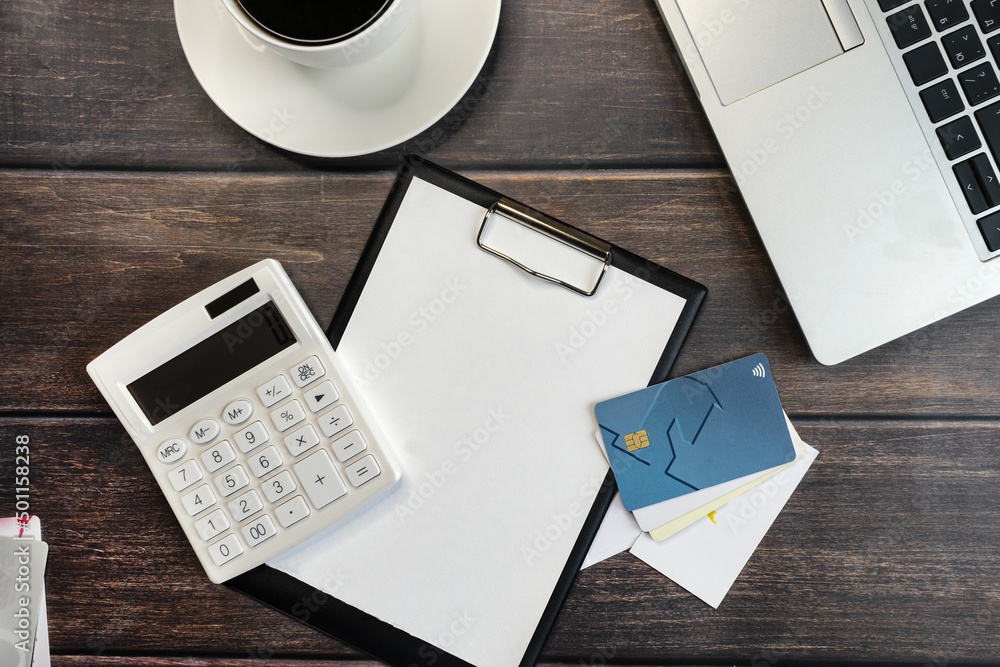 Laptop computer, calculator and notepad next to credit cards and coffee cup Laptop computer, calculator and notepad next to credit cards and coffee cup
