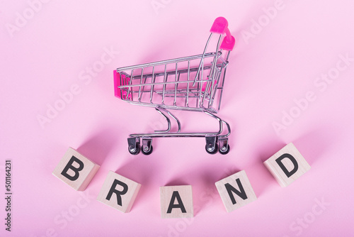 the word BRAND is written on a wooden cubes structure. Blocks on a pink background.