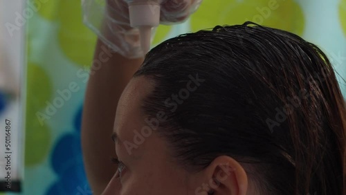 a woman dyes her hair with a brush from gray hair. applying the dye to the hair. close-up of the brunette's hair