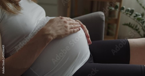 Relaxing pregnant woman strokes her belly with her hands. The expectant loving mother caresses her baby in the tummy. Belly of a pregnant woman. Maternity prenatal care and woman pregnancy concept.