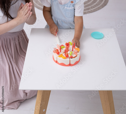 The child plays with a toy cake. The child cuts with a toy knife, tory. Child development concept photo