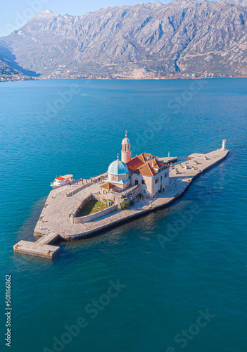 Aerial view taken with drone of the artificial island of the Church of Our Lady of the Rocks during a summer sunny day on the shores of Perast in Kotor Bay, Montenegro