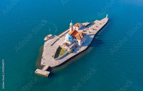 Aerial view taken with drone of the artificial island of the Church of Our Lady of the Rocks during a summer sunny day with a beautiful turquoise water on the shores of Perast in Kotor Bay, Montenegro