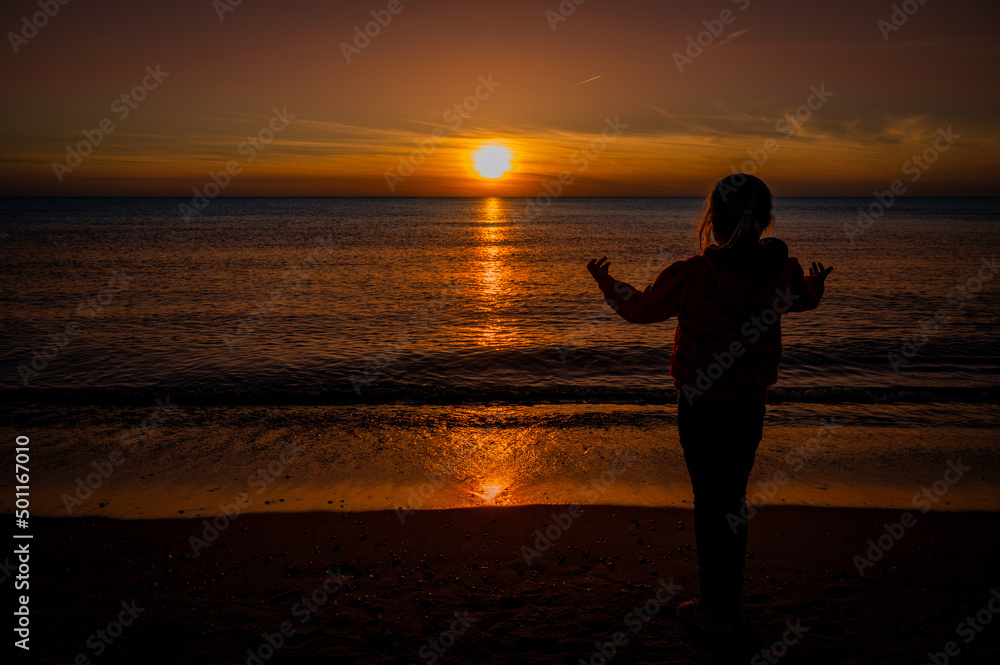 Mädchen spielt am Strand bei Sonnenuntergang