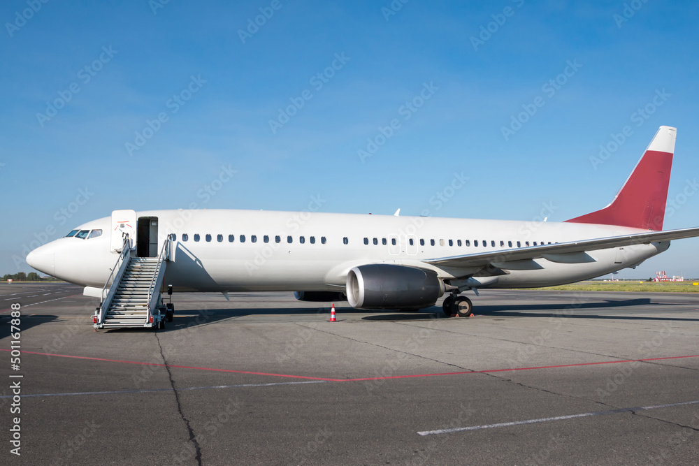 Passenger airplane with air-stairs at the airport apron