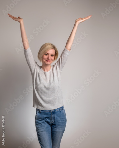 Beautiful and happy young woman on gray background with arms open