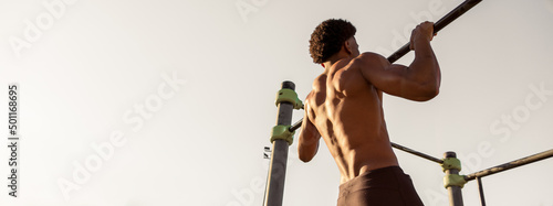 Strong guy doing pull up in a calisthenics park. Outdoor training and working out.