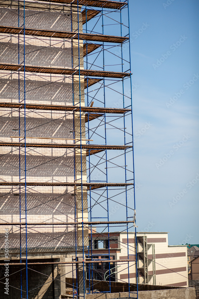 Scaffolding, metal mobile scaffold aginst blue sky background. Modern building is under construction, metal scaffolding.