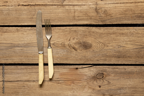 Old knife and fork lie on a wooden background, cutlery in the kitchen on the table, table