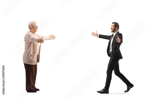 Full length profile shot of a businessman walking towards an elderly woman with arms wide open