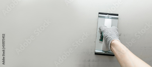 Fényképezés Plaster float in male hand in glove against a gray wall