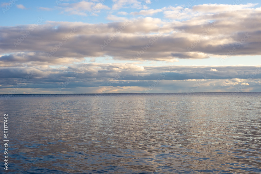 view of a calm lake against the backdrop of pre-sunset clouds
