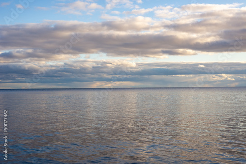 Fototapeta Naklejka Na Ścianę i Meble -  view of a calm lake against the backdrop of pre-sunset clouds