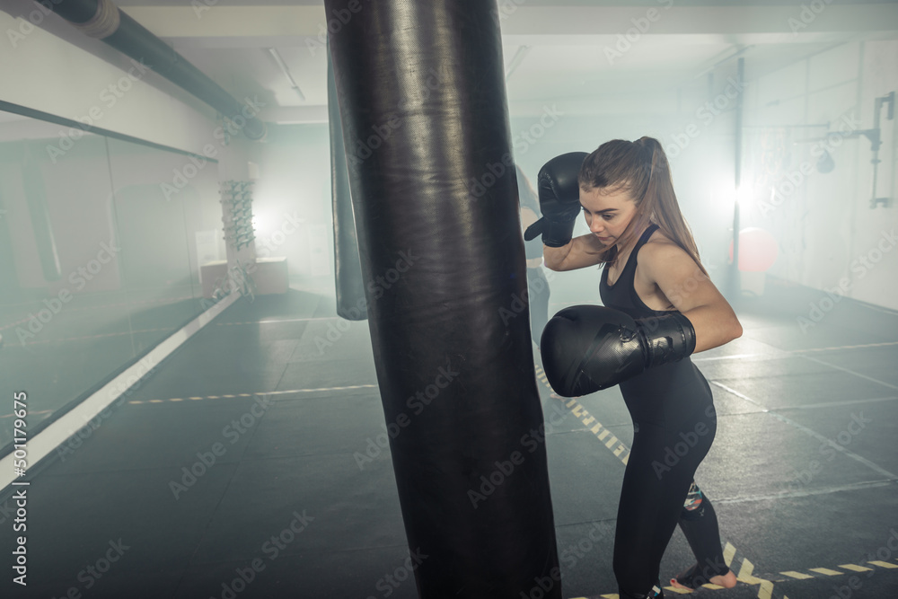 Young adult sexy woman doing back leg high kick during kickboxing.