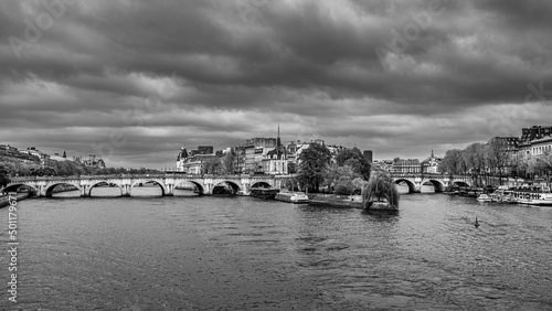 Black and white cityscape of Paris with the Pont Neuf and the Île de la Cité beliw the dense cloudy sky © petertakacs