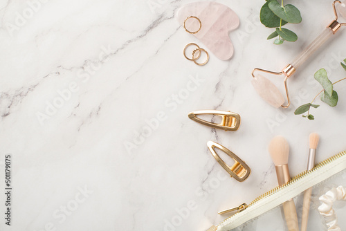 Картината върху платно Top view photo of golden barrettes rose quartz roller gua sha golden rings makeu