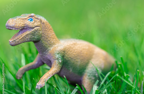 some dinosaurs toys in the green grass. happy dinosaur day  may 15 and june 1. fascinating dinosaur fantasies. spring summer outside  public park  kids having fun