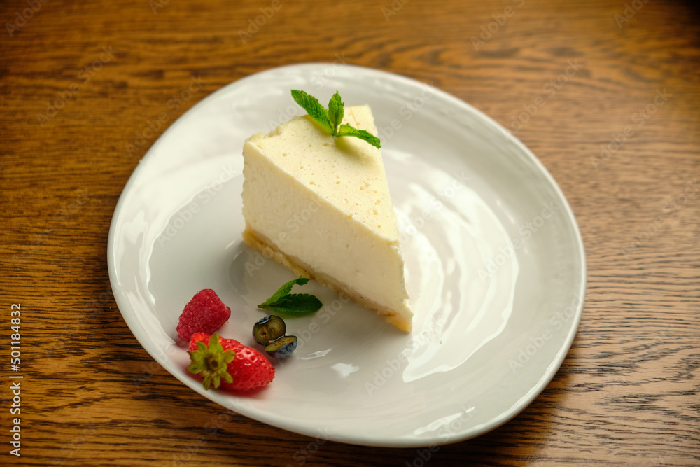 A piece of cheesecake, a classic New York-style cheesecake on a wooden table