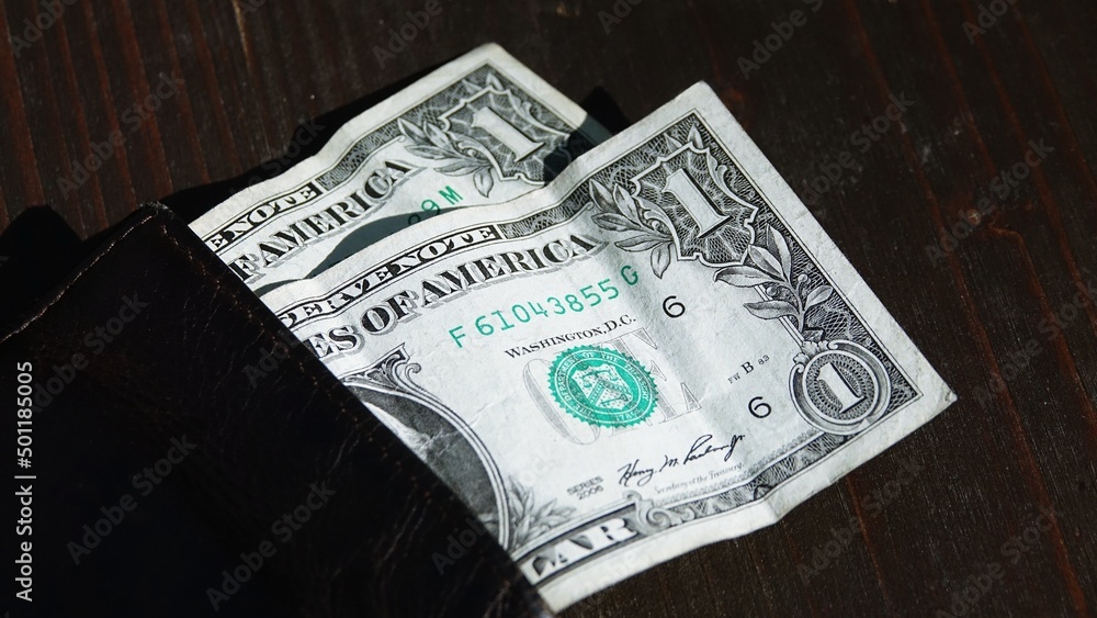 Concept of poverty, little money in your pocket: a black wallet with two one-dollar bills Concept of poverty, little money in your pocket: a black wallet with two one-dollar bills