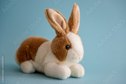 Soft toy rabbit on a blue background. © kulkann