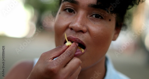 Black woman eating french fries outside during meal time