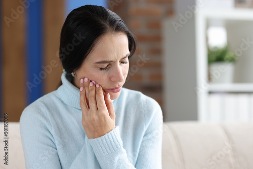 Woman holding her cheek in area of sore tooth