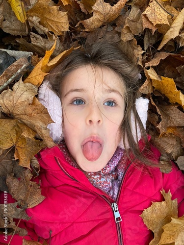 Child plaing in the park with leaves in autumn  beatufull girl  in a bunch of autumn leaves  playtime  outdoor