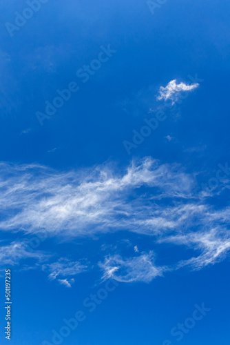 daytime blue sky with wind scattered white cirrus clouds as a natural backdrop