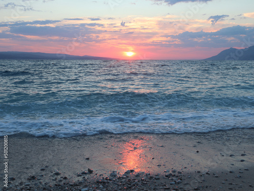 Sunset over the sea  the sky and sand on the beach are illuminated by the rays of the sun in pink  Croatia  Dalmatia  Brela