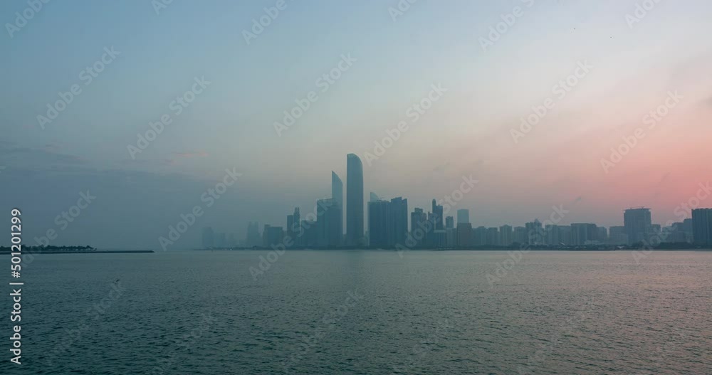 Abu Dhabi city skyline with skyscrapers before sunrise with water reflection night to day transition timelapse from the Breakwater near cultural village. Abu Dhabi city skyline with skyscrapers before sunrise with water reflection night to day transition timelapse from the Breakwater near cultural village.