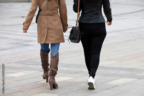 Two women walking down the street. Female fashion in spring city