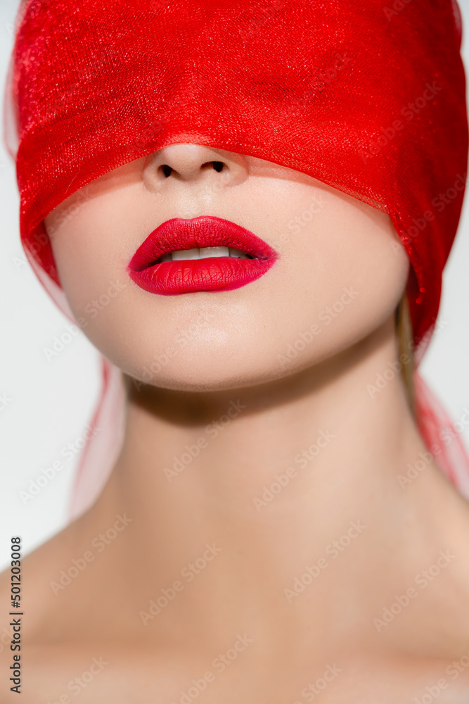 Obraz premium Young woman with red lips and fabric on face isolated on grey.