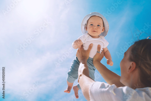 Canvas Print Mother throwing baby up against the blue sky