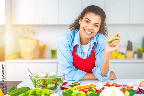 Young woman in the home kitchen prepares a genuine salad with fresh vegetables