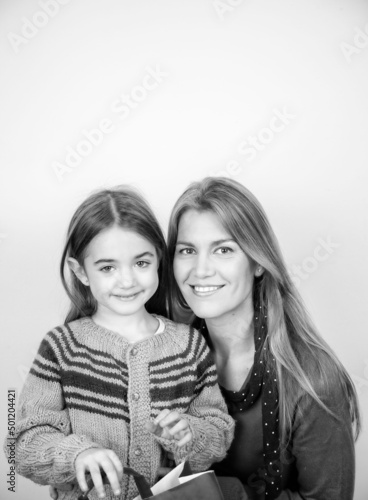 Happy young woman embracing her daughter for Christmas Day, isolated on a white background.