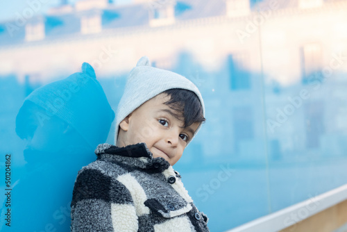 handsome boy on urban street stands next to a blue wall
