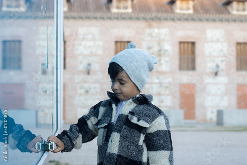 serious boy in casual clothes touches a blue wall